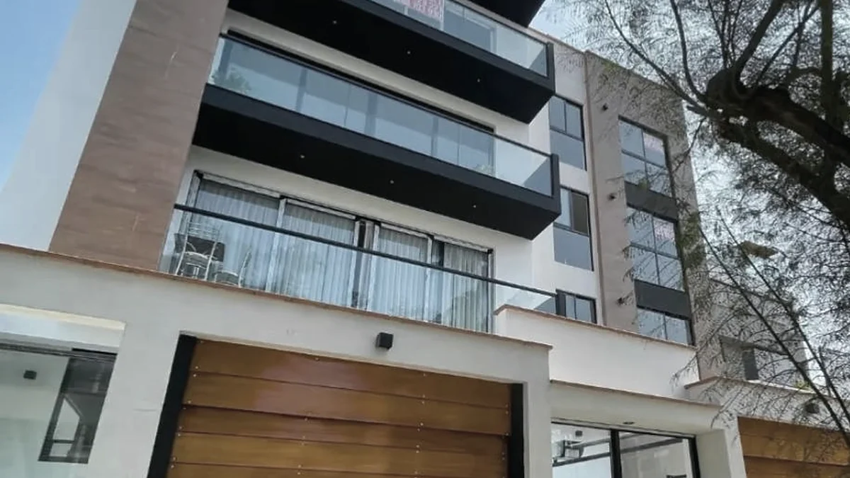 Fachada del Edificio Neptuno terminado, con balcones de vidrio y portones de madera