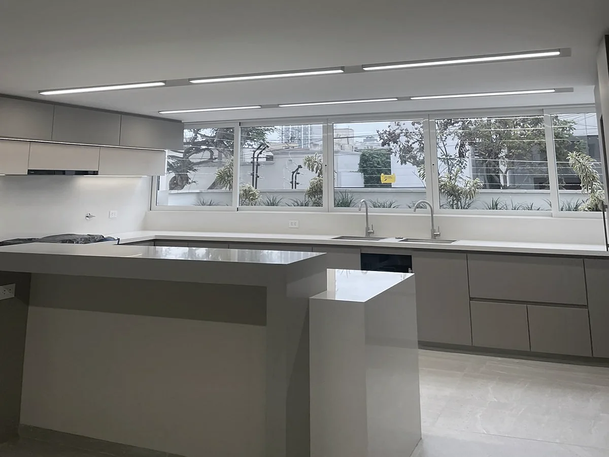 Cocina remodelada con isla, muebles grises e iluminación lineal