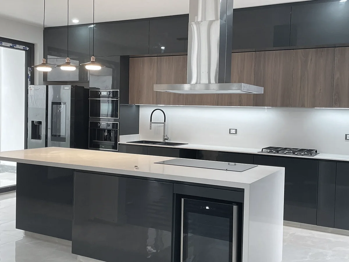 Cocina remodelada con isla, muebles oscuros y campana de acero